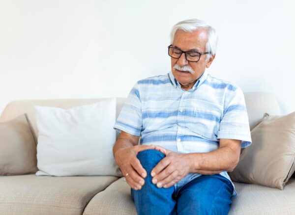 Person holding knee while standing up from office chair — knee pain after sitting
