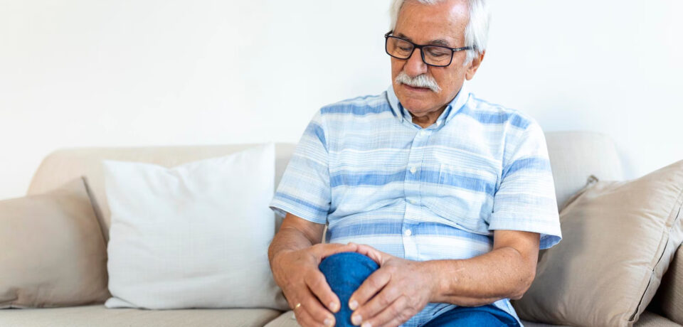 Person holding knee while standing up from office chair — knee pain after sitting